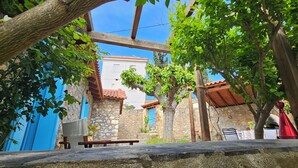 Un patio con muros de piedra, una pérgola de madera y un banco.