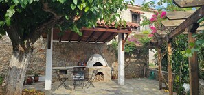 A stone building with a wooden pergola, outdoor seating, and a pizza oven. - Peloponnese Hideout-traditional stone house with amazing views and pet friendly  (Akrata)