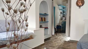 Una habitació amb terra de pedra, parets blanques, un vas blau amb flors seques i un mantell de taula blanc.