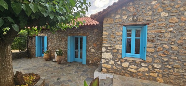 A stone building with blue shutters and a tiled roof. - Peloponnese Hideout-traditional stone house with amazing views and pet friendly  (Akrata)