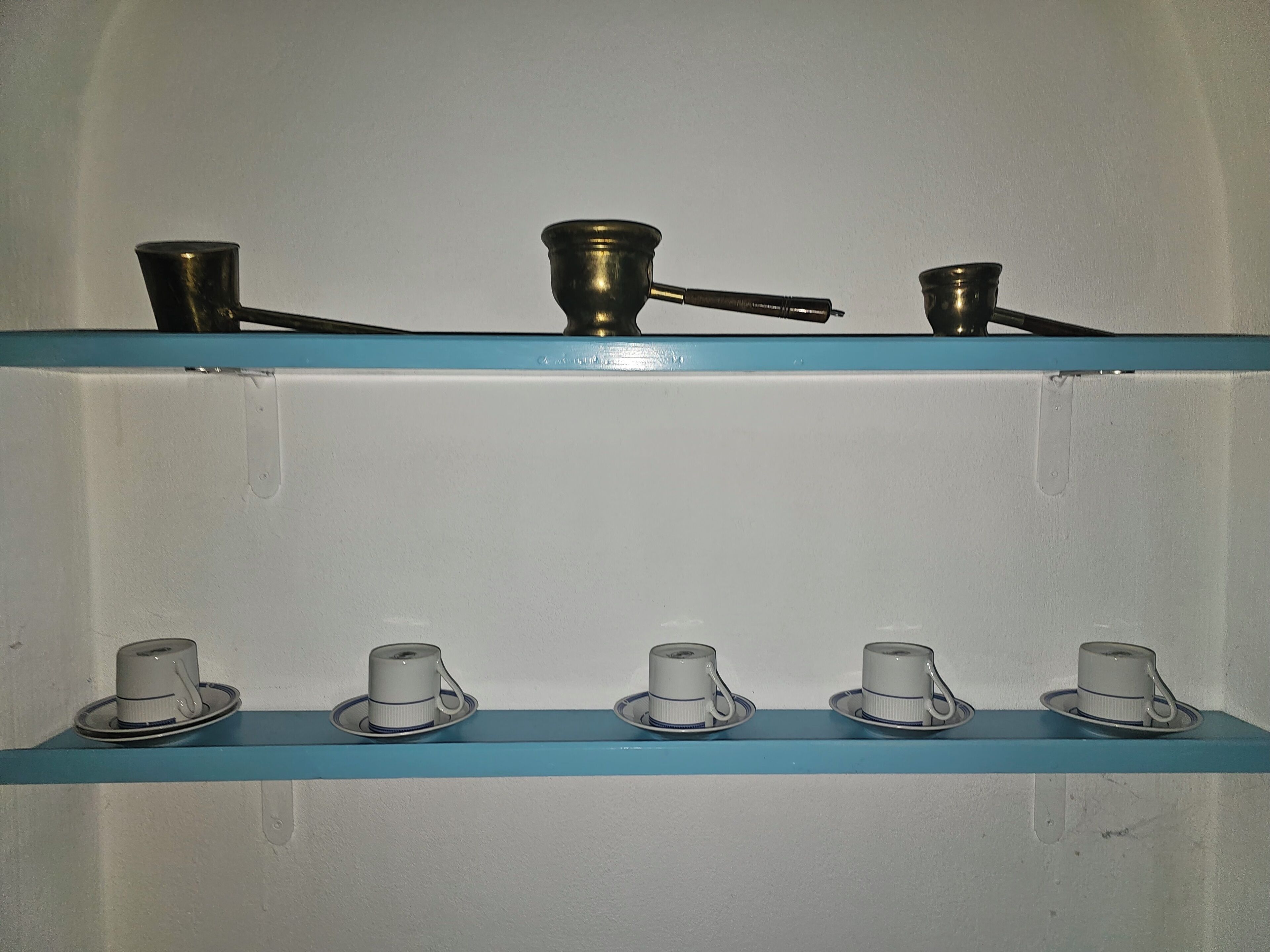 A set of shelves with metal and ceramic cups.