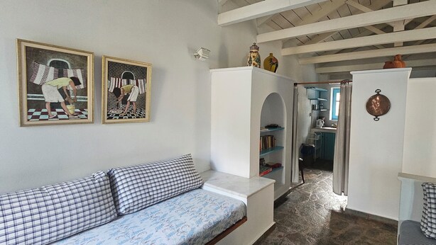 Una stanza con un divano, un armadietto bianco e un ingresso che dà su una cucina.