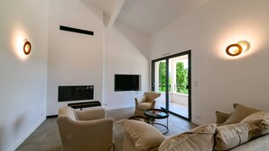 Un salon spacieux doté d’un téléviseur à écran plat, de canapés beiges, d’une table basse et d’une porte-fenêtre coulissante donnant sur un balcon.