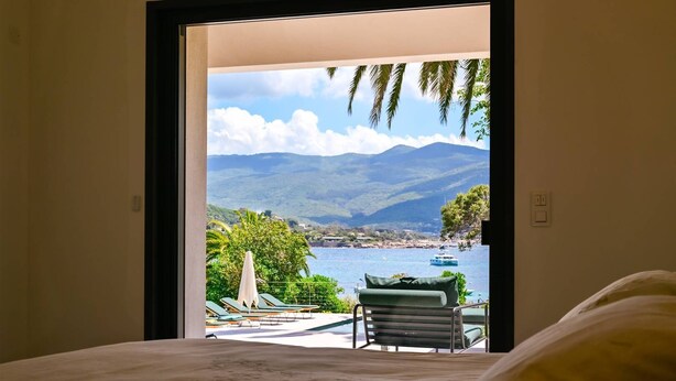 Une chambre avec vue sur un paysage côtier, comprenant des montagnes et une étendue d’eau.
