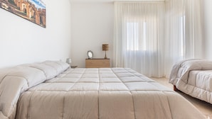 Quarto com cama grande, mesa de cabeceira, abajur e um quadro na parede.