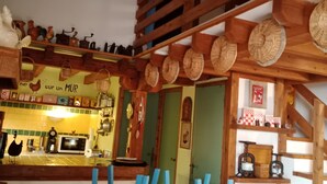 Una cocina rústica con vigas de madera, una zona de bar y un comedor con sillas azules.