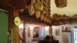 Una habitación rústica con una mesa verde de cuadros, cestas de mimbre, vigas de madera y una puerta verde.