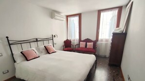 A bedroom with a bed, a chair, and a wardrobe. - Ca' Rialto Apartment (Venezia)