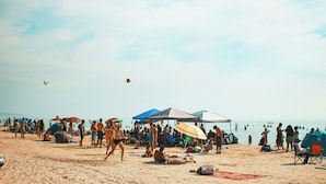 A crowded beach with people, umbrellas, and tents. - By The Beach - Affordable Sauble Beach Getaway (Sauble Beach)