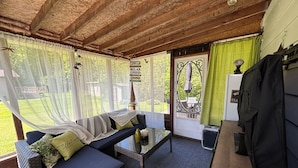 A cozy room with a sofa, a small table, and a bench. There is a door leading outside, and a sign that says "Welcome". - By The Beach - Affordable Sauble Beach Getaway (Sauble Beach)