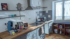 Una cocina moderna con cafetera, hervidor y varios tipos de cápsulas de café sobre la encimera.
