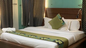 A neatly made bed with white linens and a floral-patterned bedspread. - FOSTER INN -ASAKE (Ibadan)