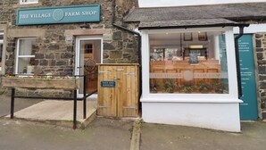 Ein Steinhaus mit einem Schild, auf dem "The Village Farm Shop" steht.
