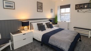 Ein modernes Schlafzimmer mit einem großen Bett, Nachttischen, einem Fenster mit Blick und einer hängenden Pflanze.