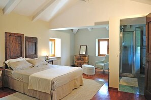 Un dormitorio con una cama grande, un aparador, una silla y un vestidor.