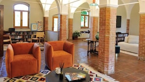 Un vaste salon doté de hauts plafonds, de murs en briques apparentes et d’un coin salon confortable avec deux fauteuils orange.