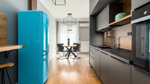 A modern kitchen with a blue refrigerator, wooden dining table, and black chairs.