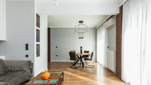 A modern living room with a grey sofa, a wooden coffee table, and a dining area with a table and chairs.