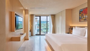 Habitación de hotel con una cama grande, un televisor montado en la pared, una puerta corrediza al balcón y un cuadro en la pared.