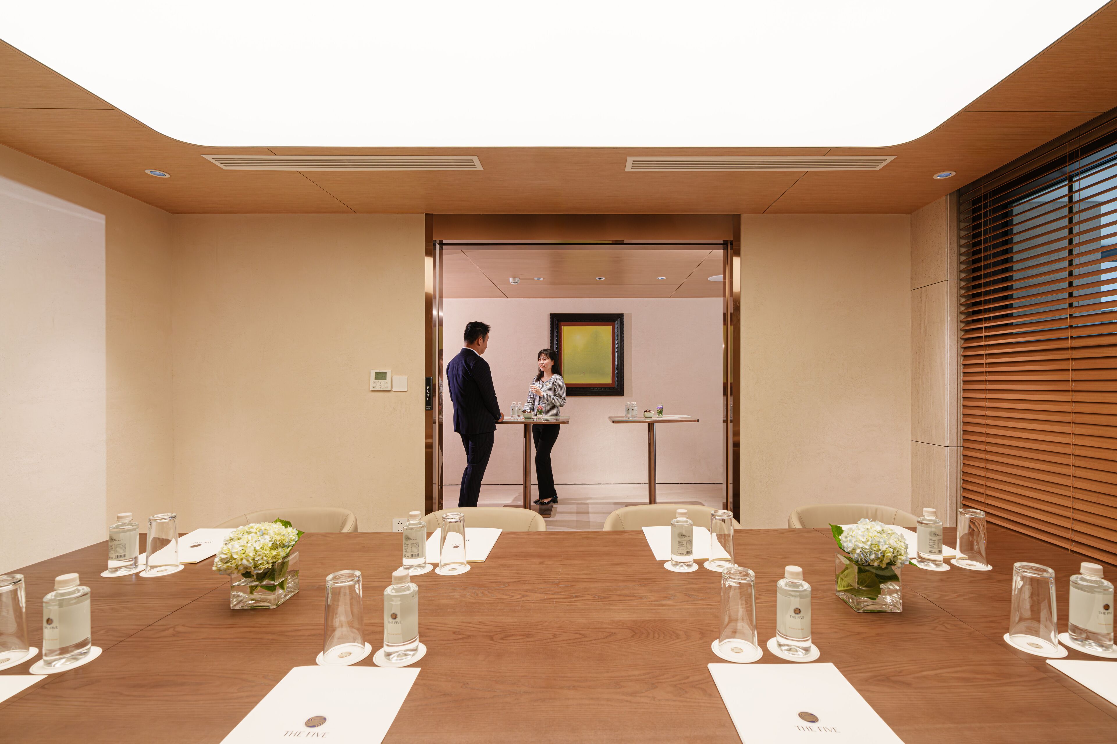 Une salle de conférence dotée d’une longue table préparée pour les réunions, avec des bouteilles d’eau et des verres à disposition.