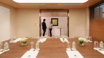 Une salle de conférence dotée d’une longue table préparée pour les réunions, avec des bouteilles d’eau et des verres à disposition.