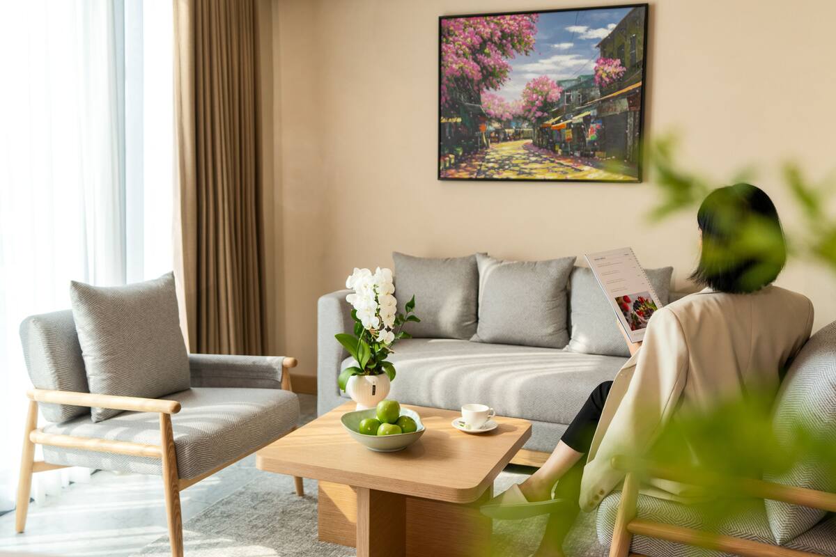 Una sala de estar moderna con un sofá, un sillón y una mesita baja con un cuenco de fruta y un florero.