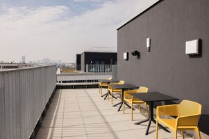 Una terraza en la azotea con mobiliario exterior y vistas a la ciudad.
