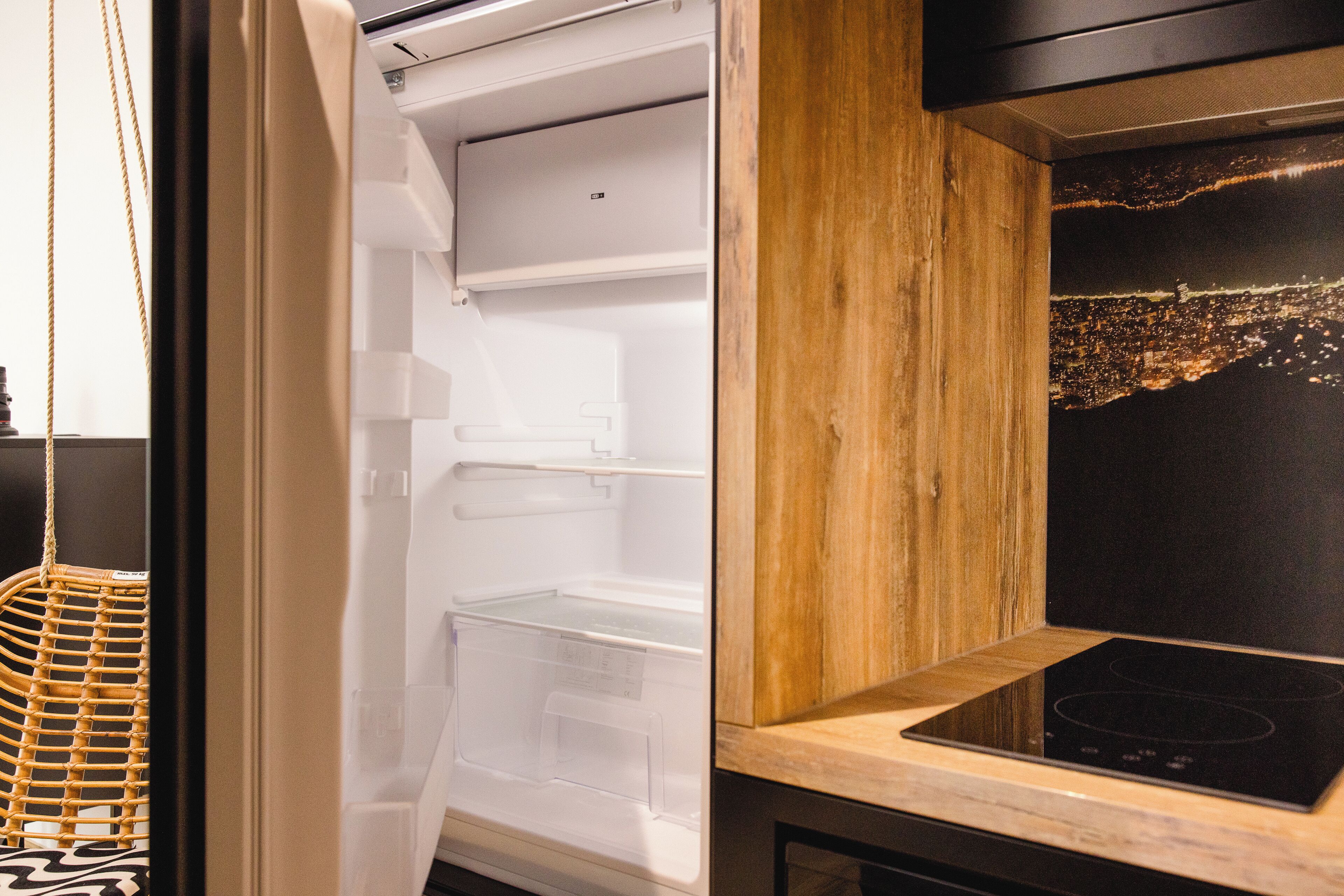 Eine moderne Küche mit integriertem Kühlschrank, Holzschränken und einer städtischen Szene an der Wand.