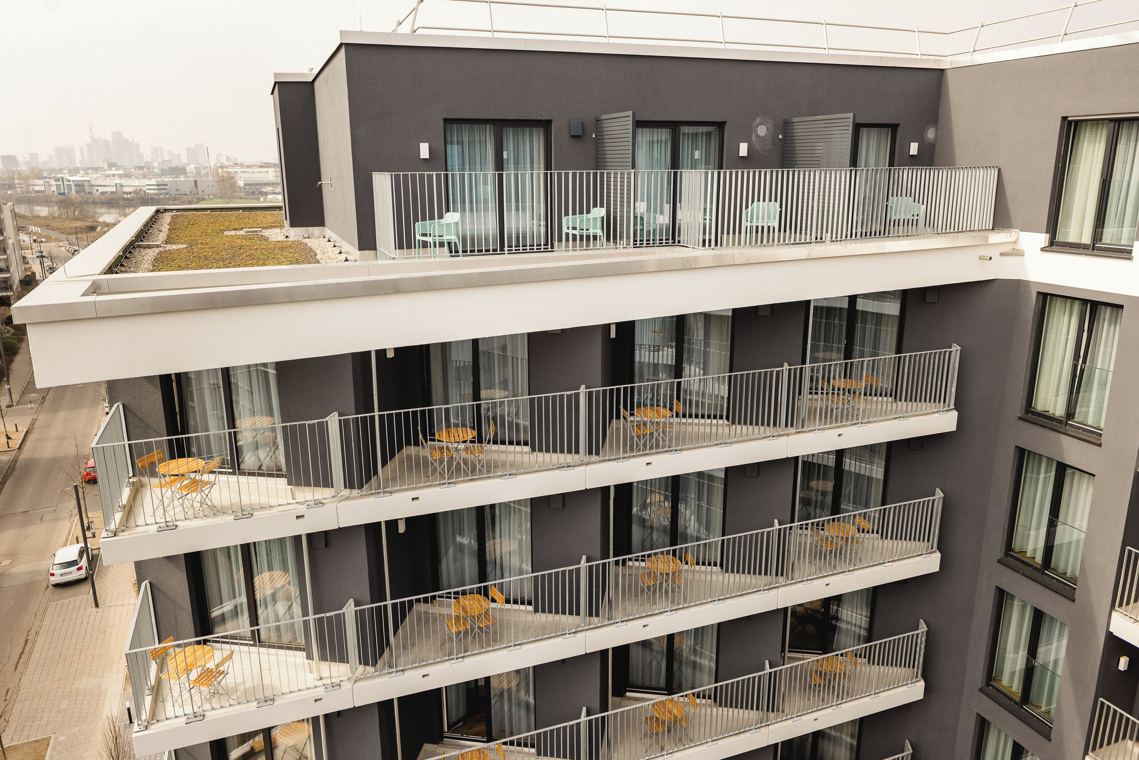 A multi-story building with balconies, large windows, and a rooftop garden.