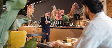 A restaurant with a mural of a hummingbird and a statue of a robed figure.
