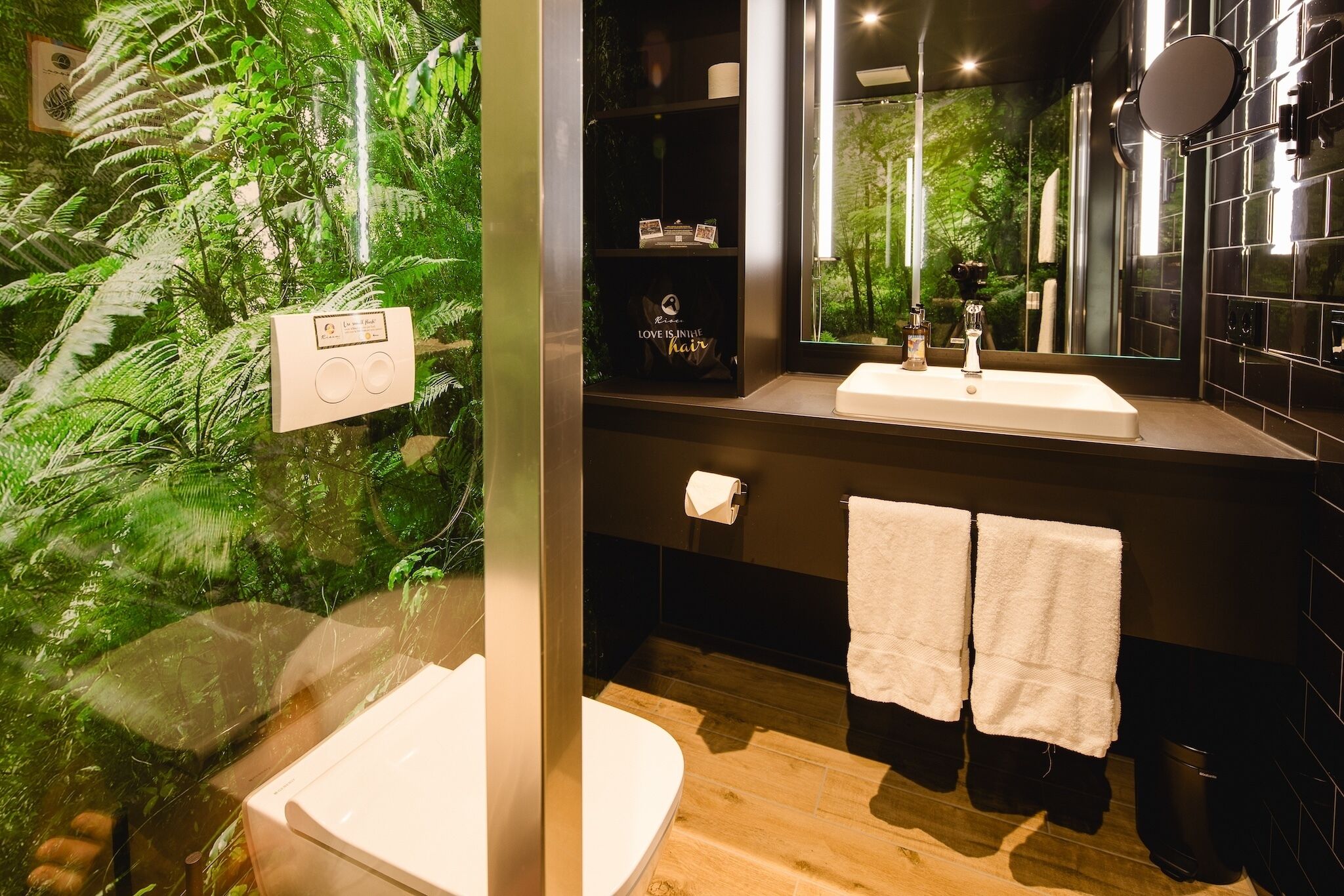 A modern bathroom with a glass partition, a sink, a mirror, and a toilet.