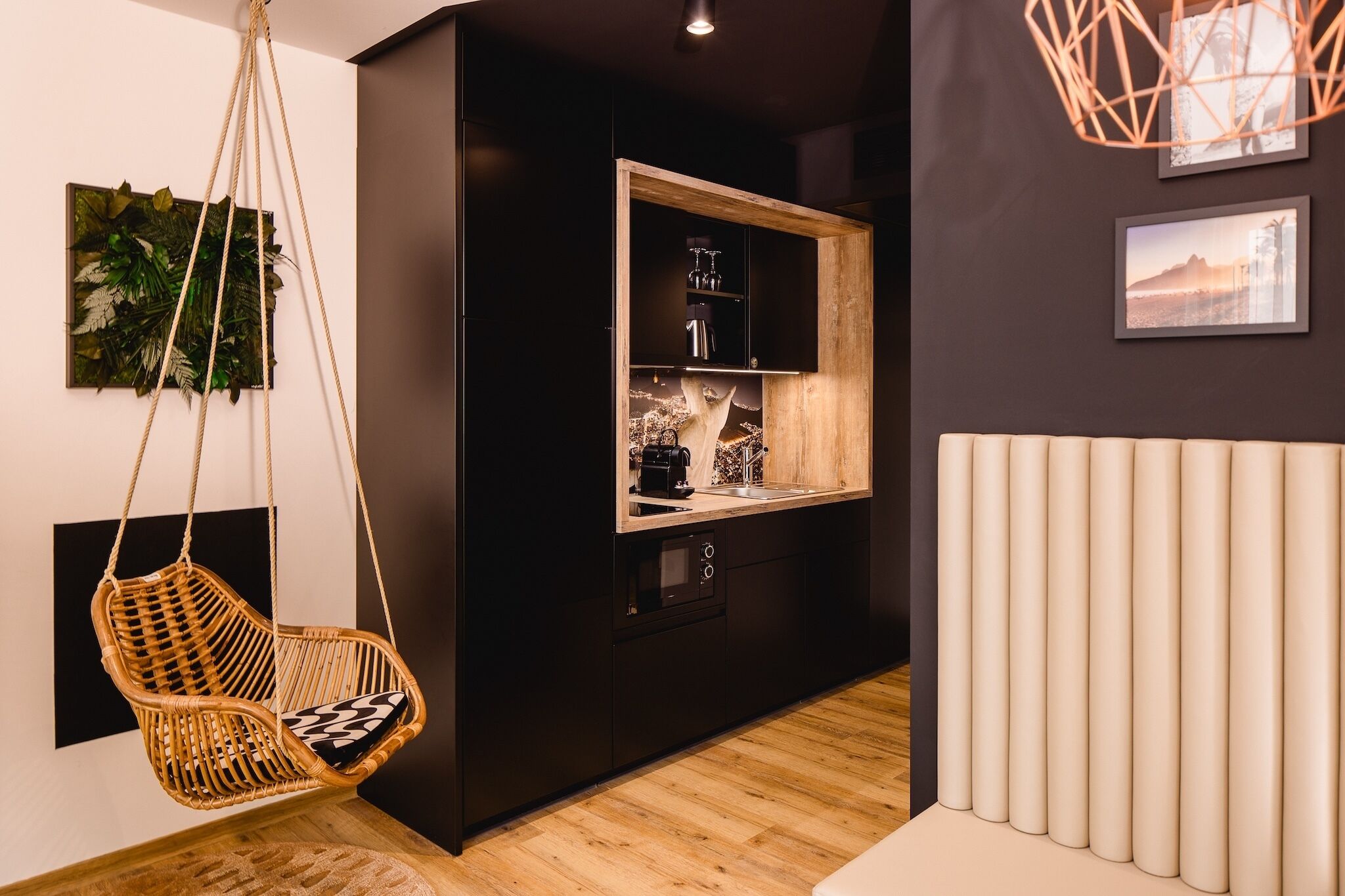A modern kitchen with a hanging chair, built-in appliances, and a wooden cabinet.