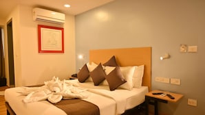 Habitación de hotel con cama, mesita de noche con lámpara, aire acondicionado y un cuadro en la pared.