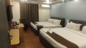 Habitación de hotel con dos camas, un escritorio, una silla y un equipo de aire acondicionado.