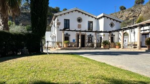 A building with a courtyard, outdoor seating, and a stone wall. - Hotel La Hoya del Tajo (Ronda)