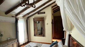 A bedroom with a large bed, wooden beams, a mirror, and a bedside table. - Hotel La Hoya del Tajo (Ronda)