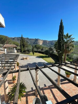 A terrace with a view of a mountainous landscape, featuring a pergola, potted plants, and a paved area. - Hotel La Hoya del Tajo (Ronda)