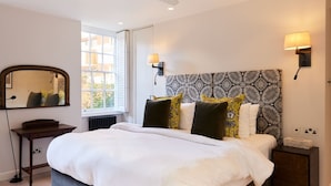 A bedroom with a bed, bedside tables, a mirror, and patterned headboard. - The Chelsea Haven - Glamorous 1bdr Flat (London)