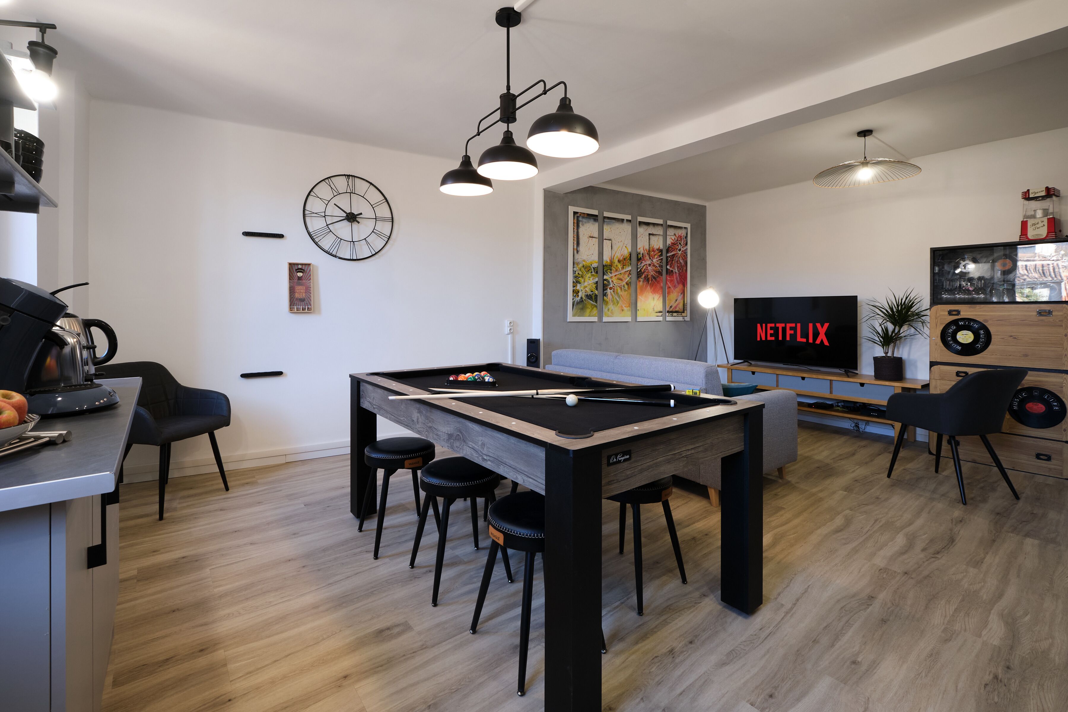 A modern living room with a pool table, bar area, and a large flat-screen TV displaying 'NETFLIX'.