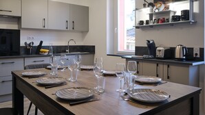 Una cocina moderna con una mesa de comedor preparada para seis personas, equipada con platos, vasos y cubiertos.