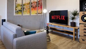 Una sala de estar moderna con un sofá gris, un mueble de entretenimiento de madera y un televisor de pantalla plana grande mostrando 
