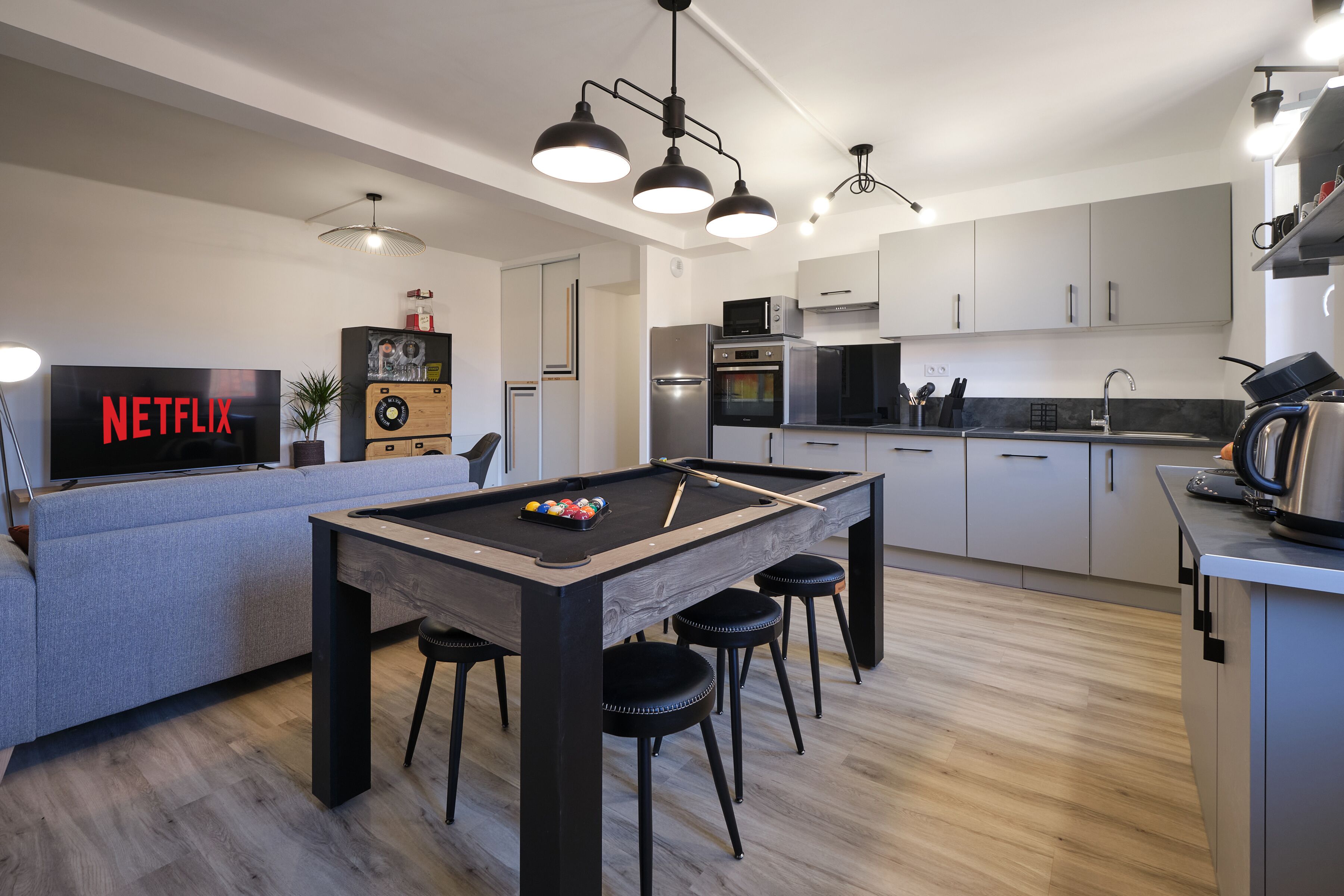 Een moderne keuken met een pooltafel, een televisietoestel waarop het Netflix-logo te zien is, en een bar.