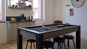Una cocina moderna con mesa de billar, taburetes de bar y estación de café.