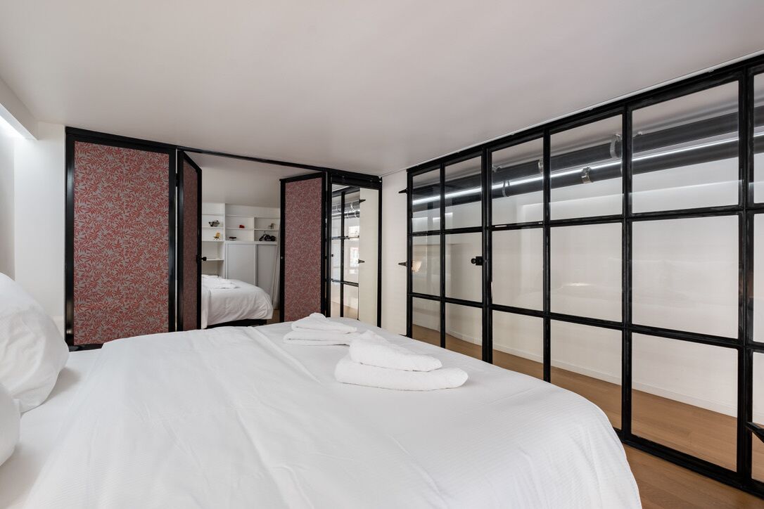Habitación de hotel con una cama, un armario con puerta corredera y vistas a través de la puerta.