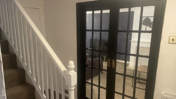 A staircase with white railings and a black door with glass panels. - 4 Bedroom House - Sleeps 6 - Garden, Bbq, Parking (Birmingham)