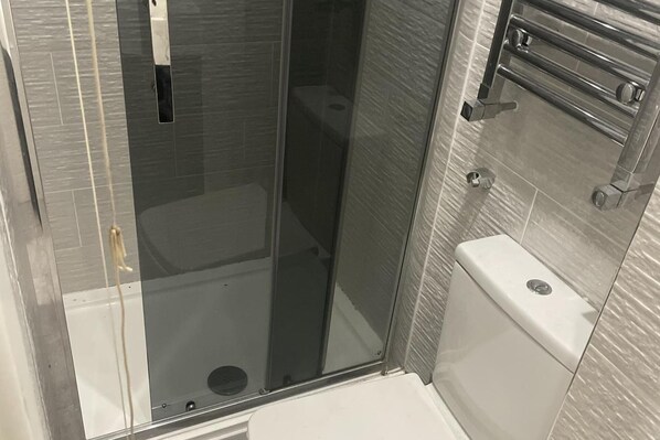Un baño moderno con cabina de ducha de vidrio, inodoro y perchero para toallas.