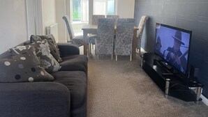 A living room with a sofa, chairs, a TV, and a window. - 4 Bedroom House - Sleeps 6 - Garden, Bbq, Parking (Birmingham)