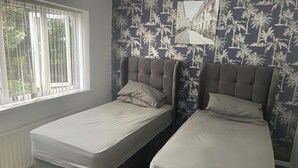 A room with two single beds, a radiator, and a window with curtains. - 4 Bedroom House - Sleeps 6 - Garden, Bbq, Parking (Birmingham)