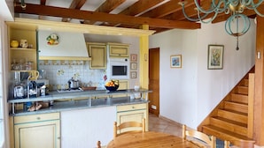 A kitchen with wooden cabinets, a central island, and a dining table with chairs. - KERDERFF - Holiday home for rent, between beach and forest, Carnac - TK30 (Carnac)