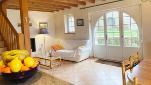A cozy living room with a white sofa, a glass coffee table, and a wooden dining table. - KERDERFF - Holiday home for rent, between beach and forest, Carnac - TK30 (Carnac)